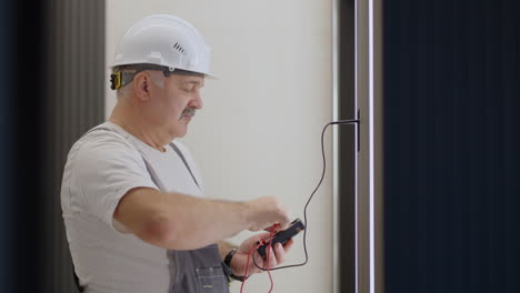 Elderly-Electrician-checks-the-operation-of-the-wall-control-unit-of-lamps-with-the-system-of-a-modern-house-after-installation-and-repair